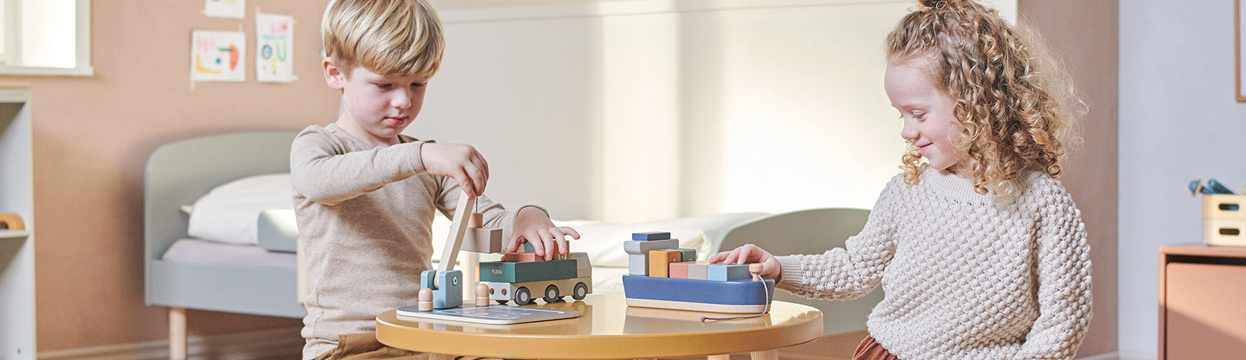 Siblings playing with wooden container ship, truck and crane