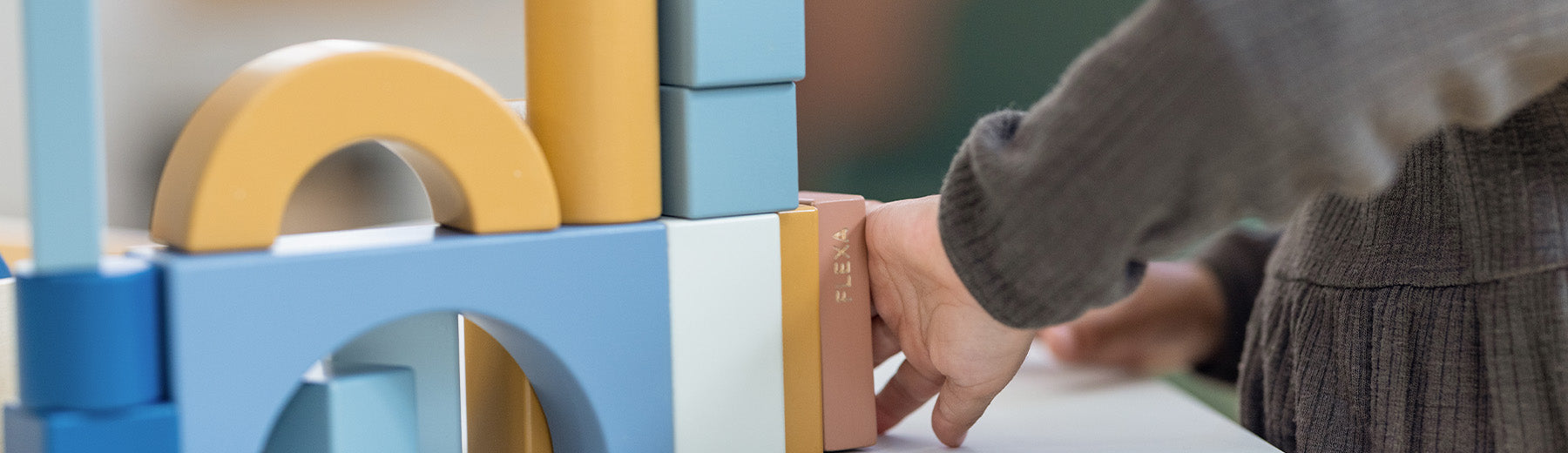 child playing with wooden stacking toys from FLEXA
