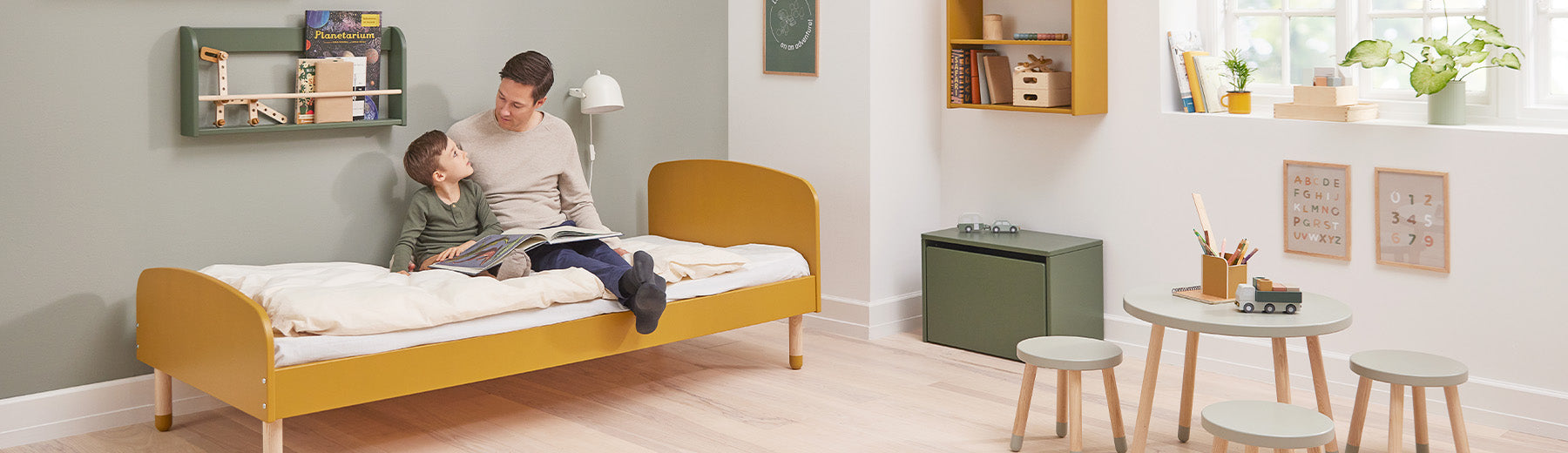 Father and son sitting in a Dots single bed from FLEXA