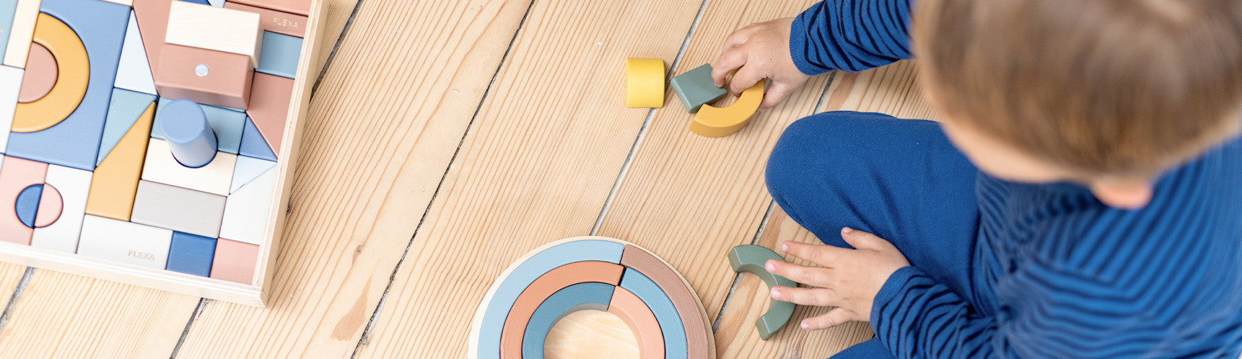 Little boy playing with wooden creative blocks and puzzles from FLEXA