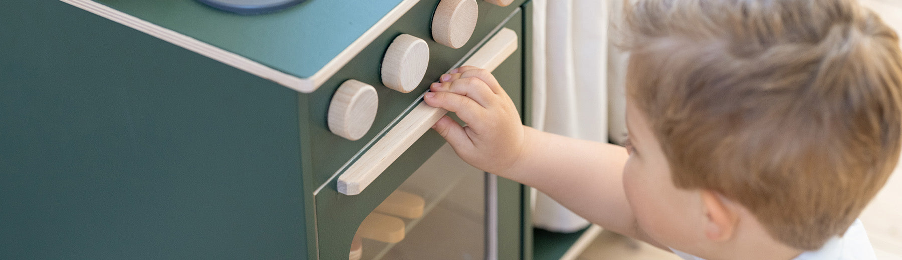 Boy playing with his wooden play kitchen from FLEXA