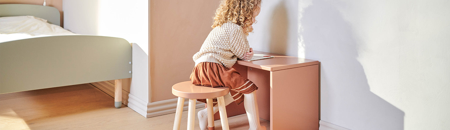 Child is sitting on a wooden stool from FLEXA