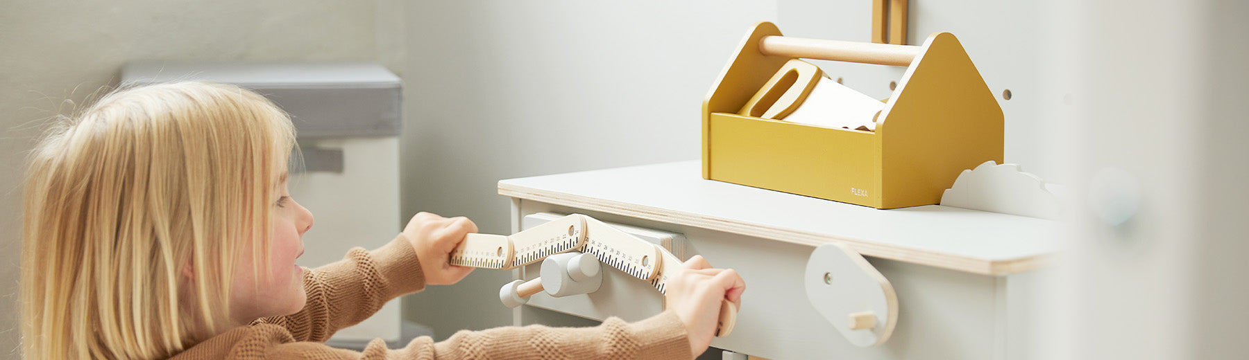 Child is playing with his wooden workbench and tools from FLEXA