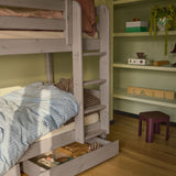 FLEXA CLASSIC Etagenbett mit blau gestreifter Bettwäsche, Leiter, Kiefernholz-Schubladen und Regalen in einem Kinderzimmer; kindersichere Ausführung erkennbar.