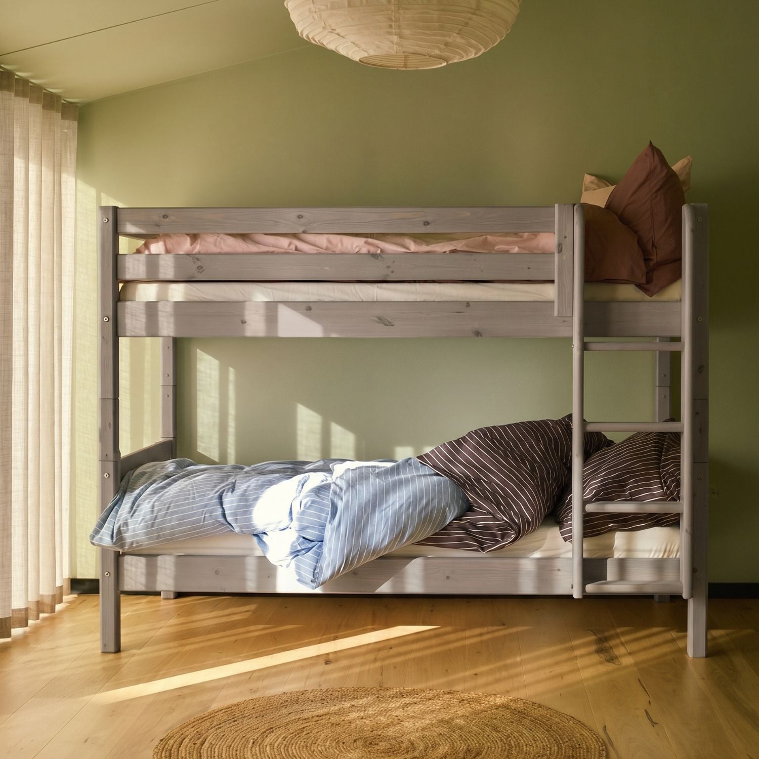 FLEXA bunk bed with straight ladder, white finish, shown in a green-walled sunlit bedroom with wood floors and round rug.