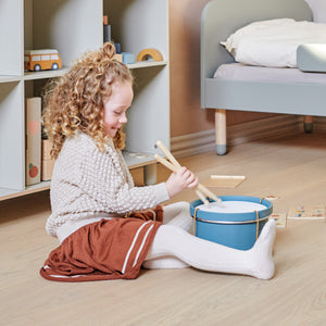Next to a FLEXA single dots bed a girl is playing with her wooden drum from FLEXA