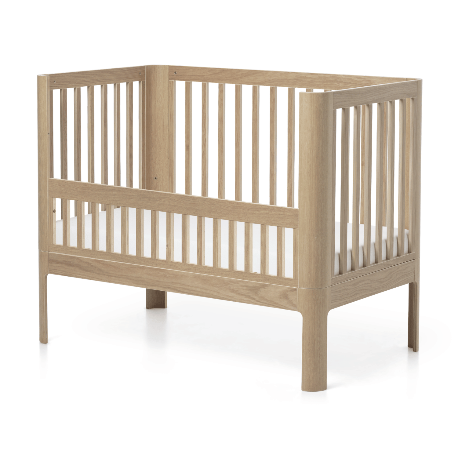 FLEXA NOVA Babybettgitter aus Eiche mit Lattenrost und Matratze, kindersichere Ausführung, abgebildet vor dem Hintergrund eines weißen Schlafzimmers.