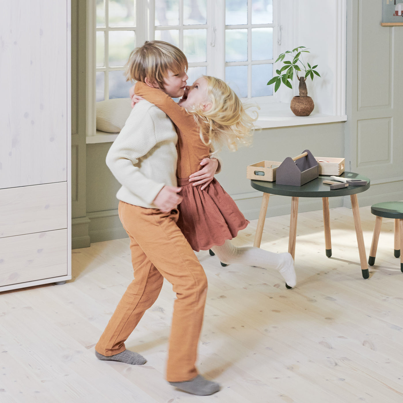 Siblings dancing in from of the Dots table and stools from FLEXA