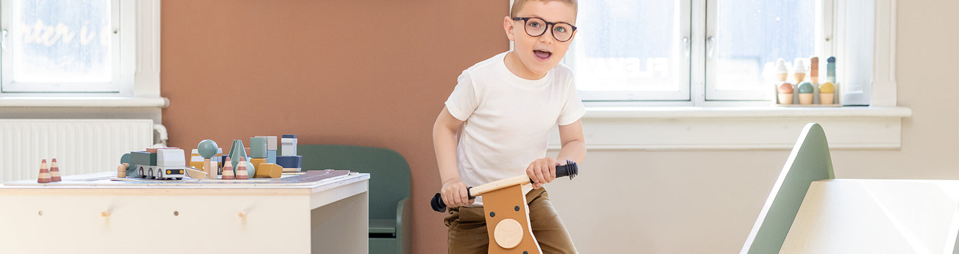 Boy is riding his wooden balance bike 