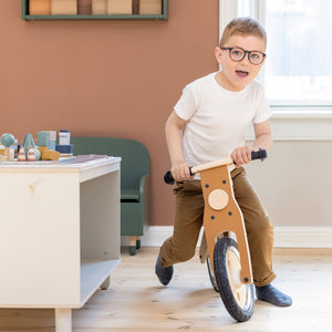 Boy is having fun while riding his balance bike from FLEXA next to the play table