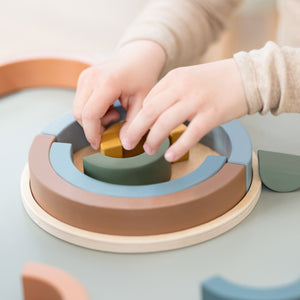 Child is playing with the wooden rainbow puzzle from FLEXA