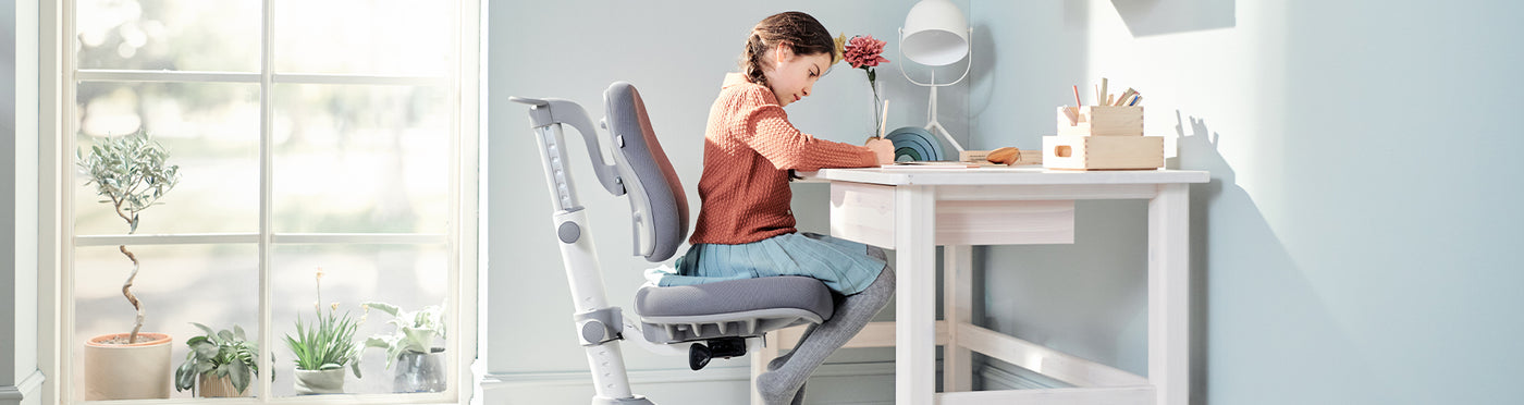 Girl is sitting on her Verto study chair and Classic table with drawer from FLEXA
