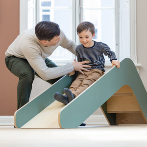 Boy is sliding down a wooden slide from FLEXA