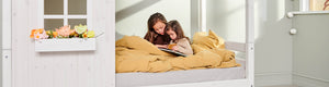 Girls are sitting in the Classic house bed from FLEXA