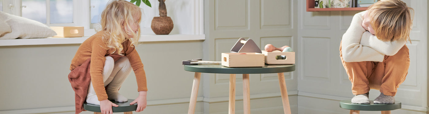Boy and girl is playing at the Dots play table and stools in deep green from FLEXA